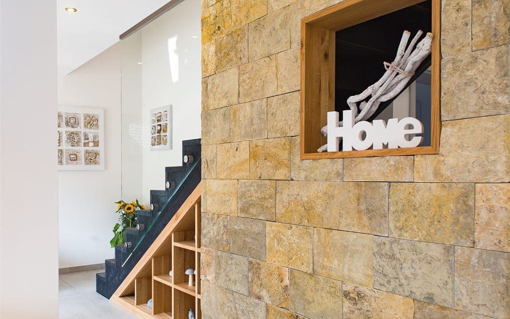 Jedermann®-Musterhaus: Flur mit Treppe und Natursteinwand